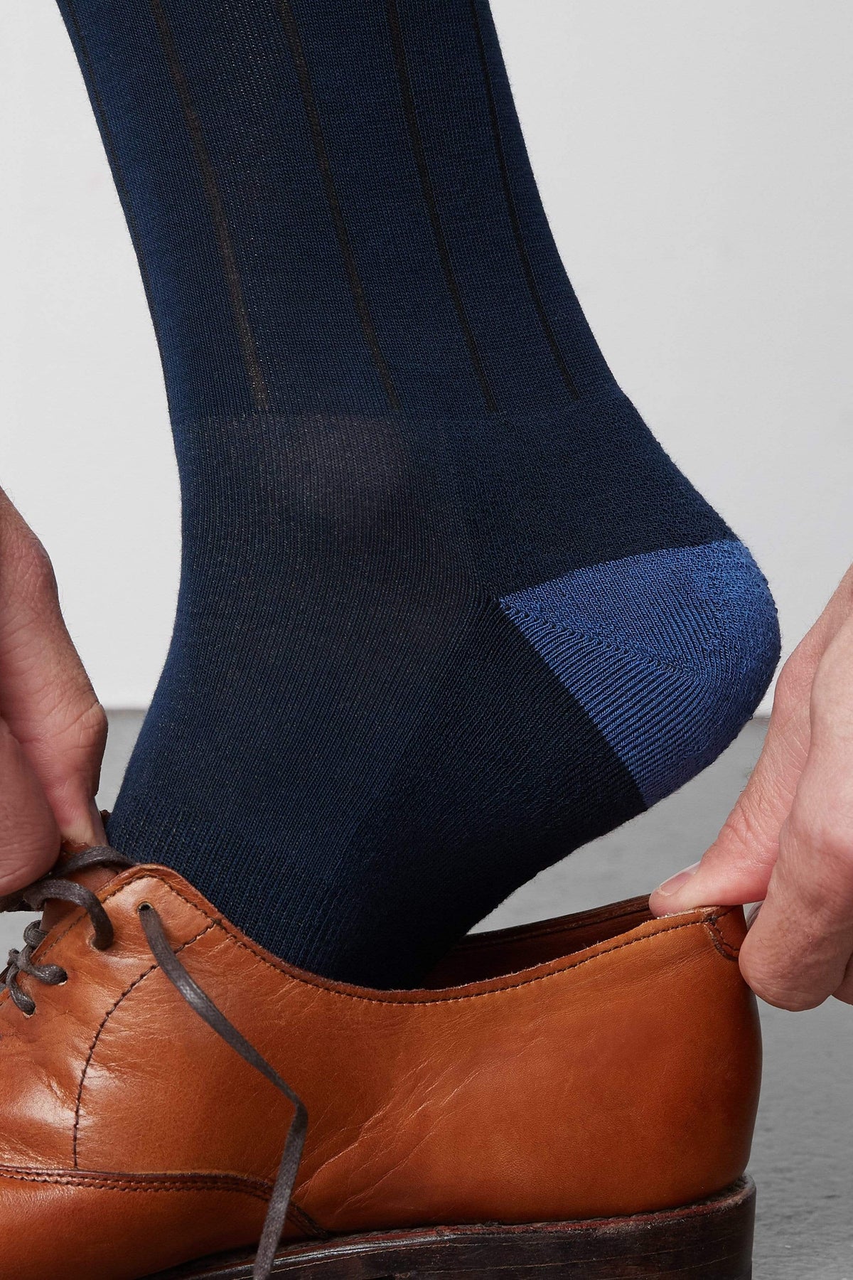 Guy putting on dress shoe while wearing the Silver Extended Crew Sock