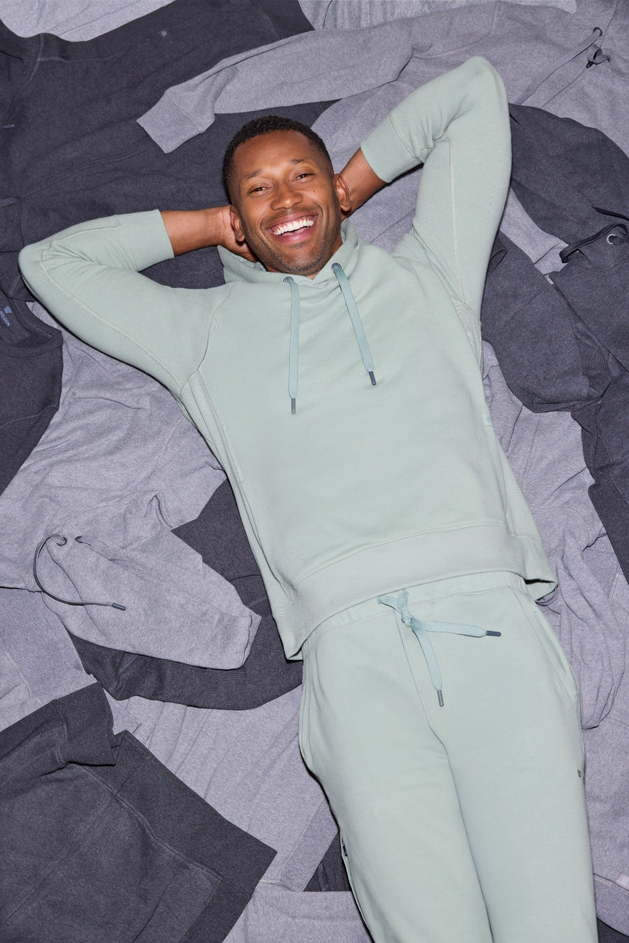 May wearing ACE Hoodie and ACE Sweatpants and laying on a bed of ACE clothing