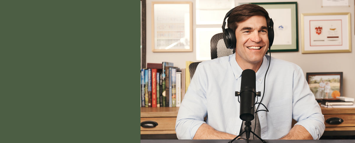 Shane Bacon wearing headphones and recording with a microphone, wearing Dean Oxford.