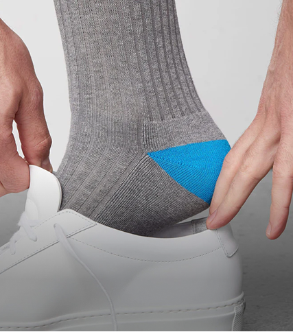 close up image of a man wearing an extended sock and putting his shoe on