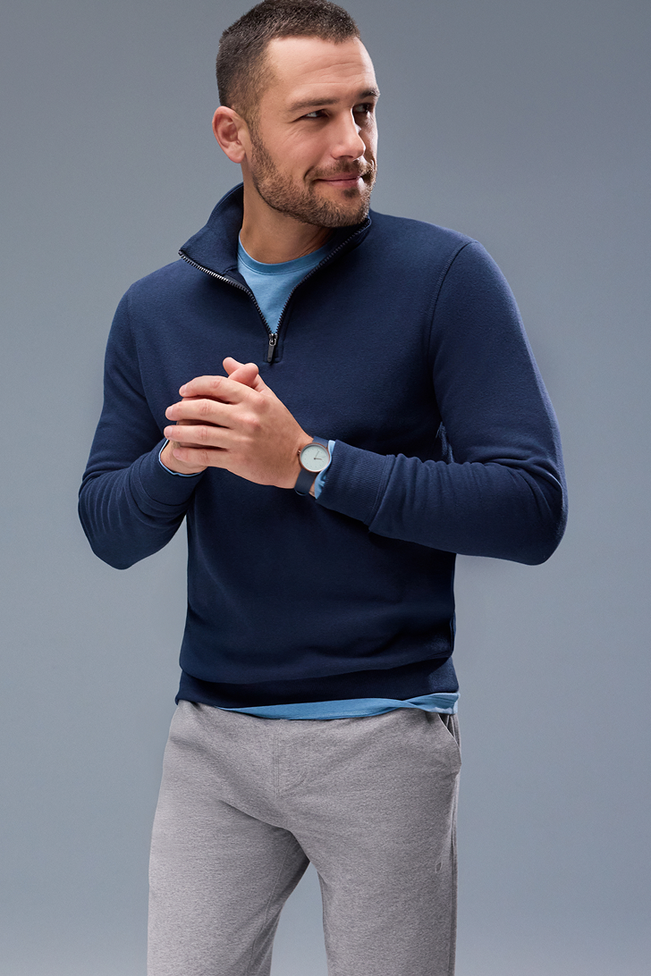 Man wearing a navy blue pullover with a gray background