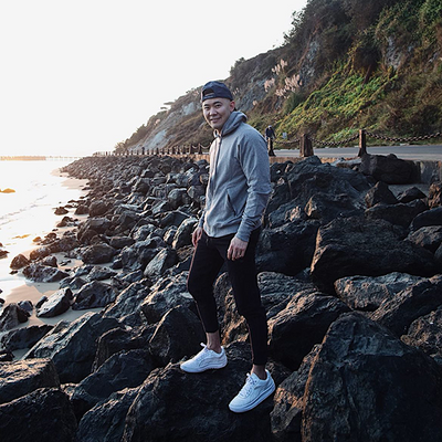 Man standing on rocks on the side of the sea wears Mack Weldon clothing