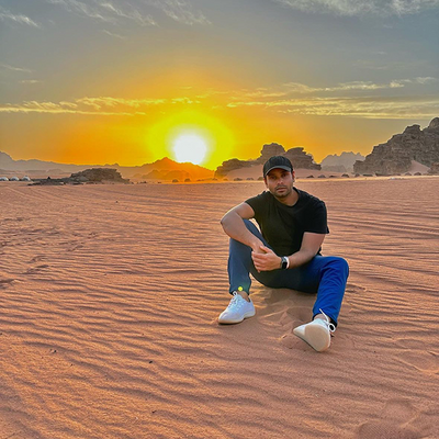 man sitting in the middle of a sandy desert wearing Mack Weldon clothing