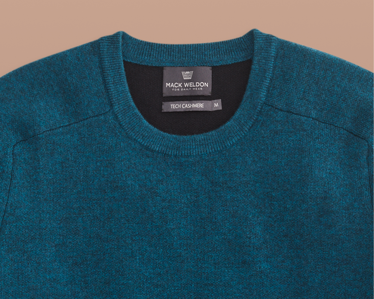 Teal sweater with Mack Weldon label on a beige background
