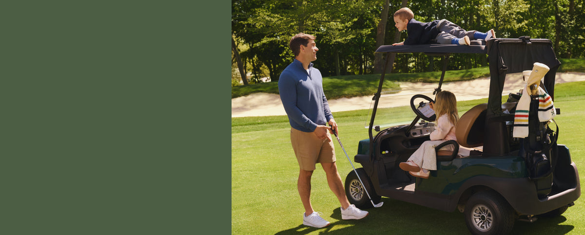 Man wearing Stretch twill chino shorts playing with his children. With one riding on the roof of the golf cart while one is sitting.