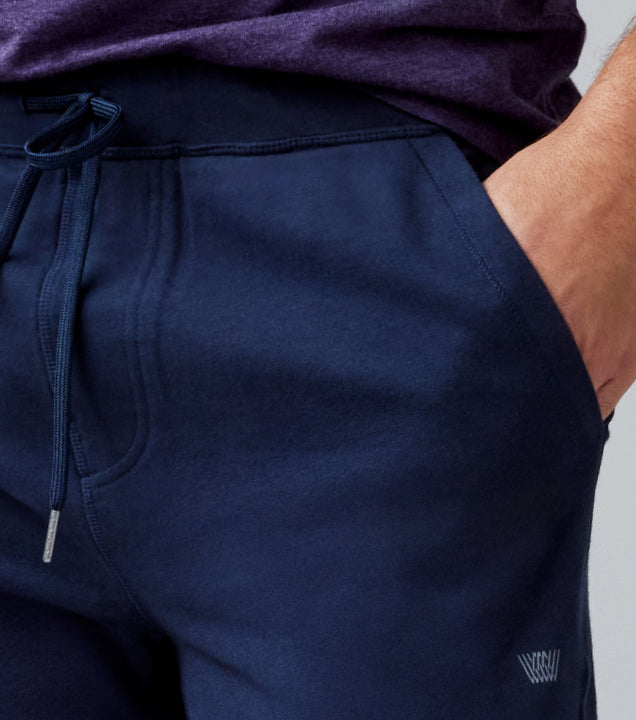 close up image of a man's hand in the pocket of his ACE sweatshorts