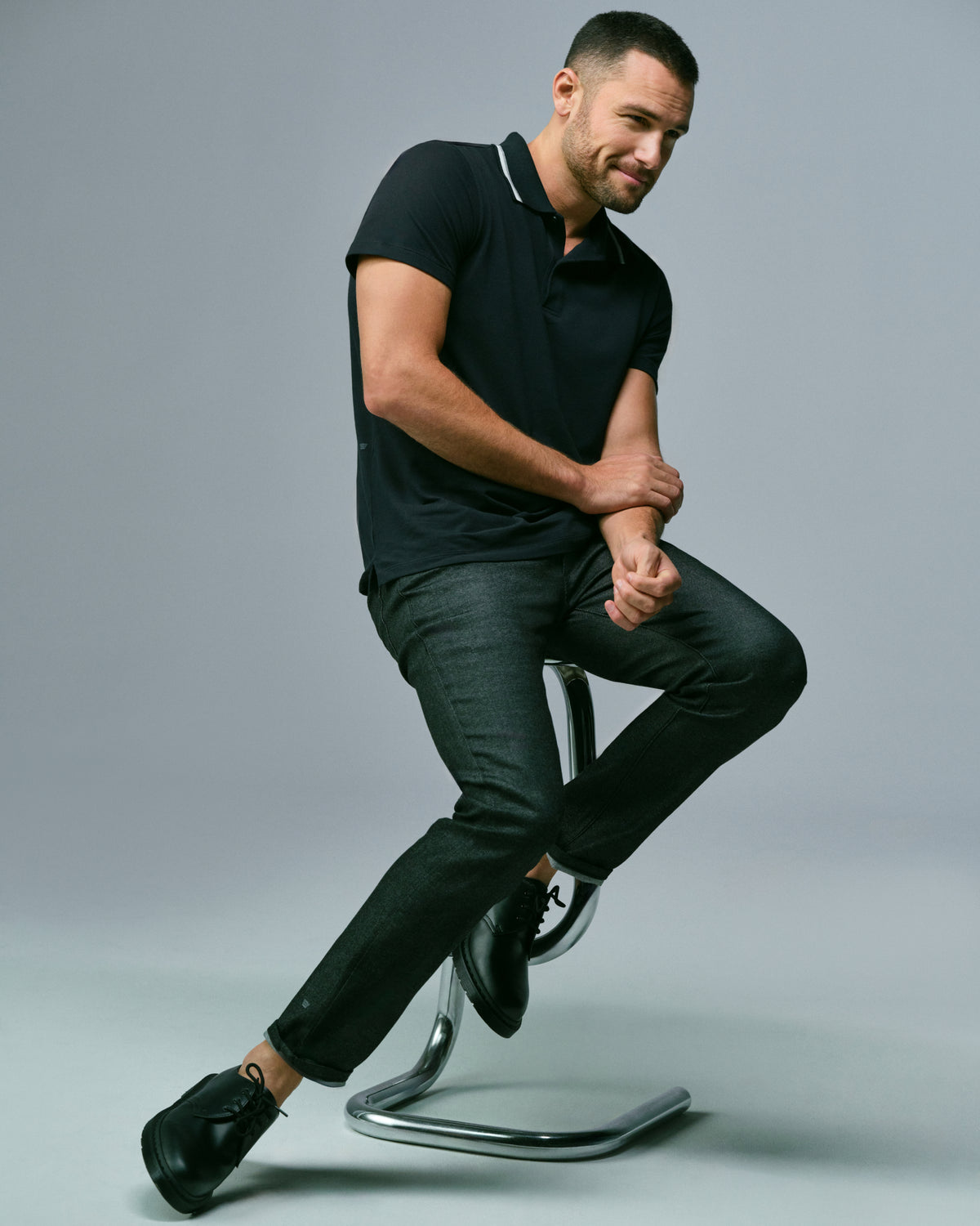Man sits on a stool wearing SILVER Denim jeans and SILVER polo