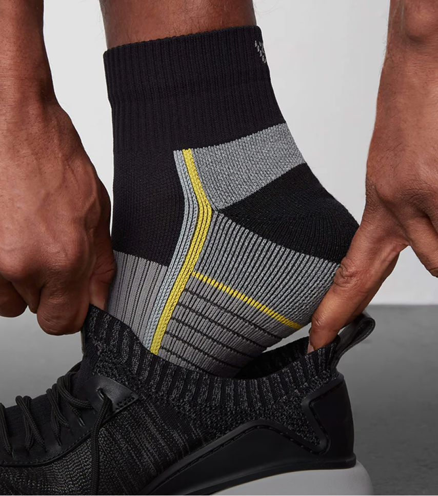 Close up of a man wearing AIRKNITx High Ankle socks and putting them into a shoe
