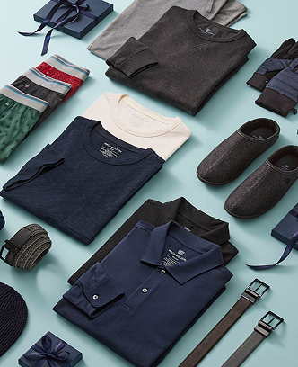 Collection of folded shirts, shoes, and accessories on a light blue background